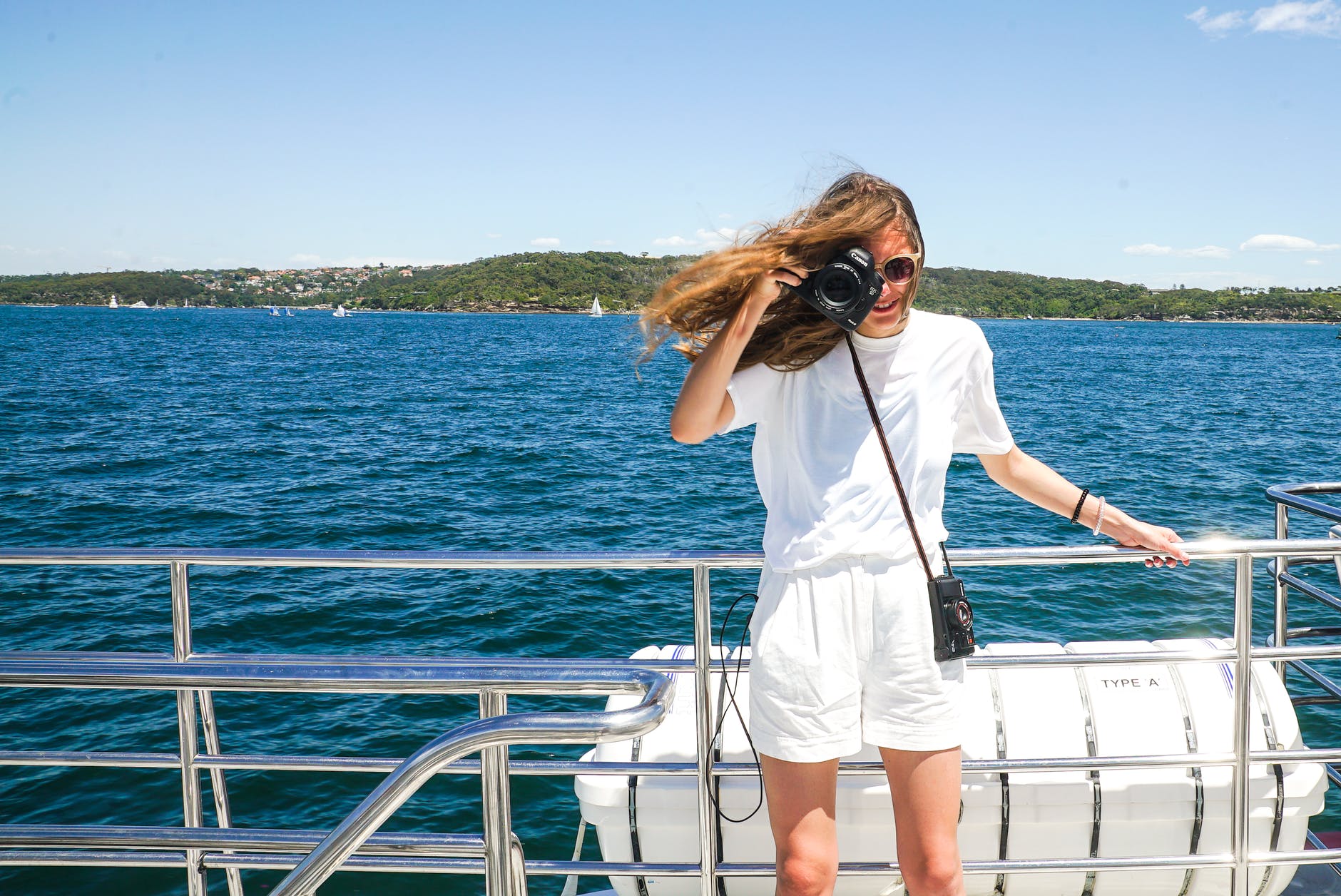 woman capturing photo while holding hand rails on boat