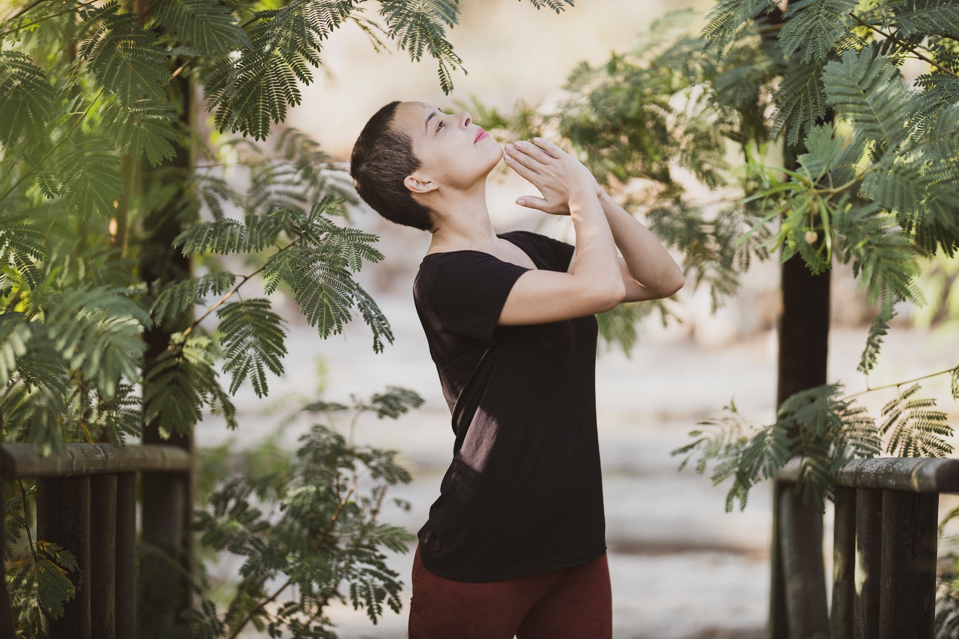 woman wearing black crew neck t shirt standing near leafy trees