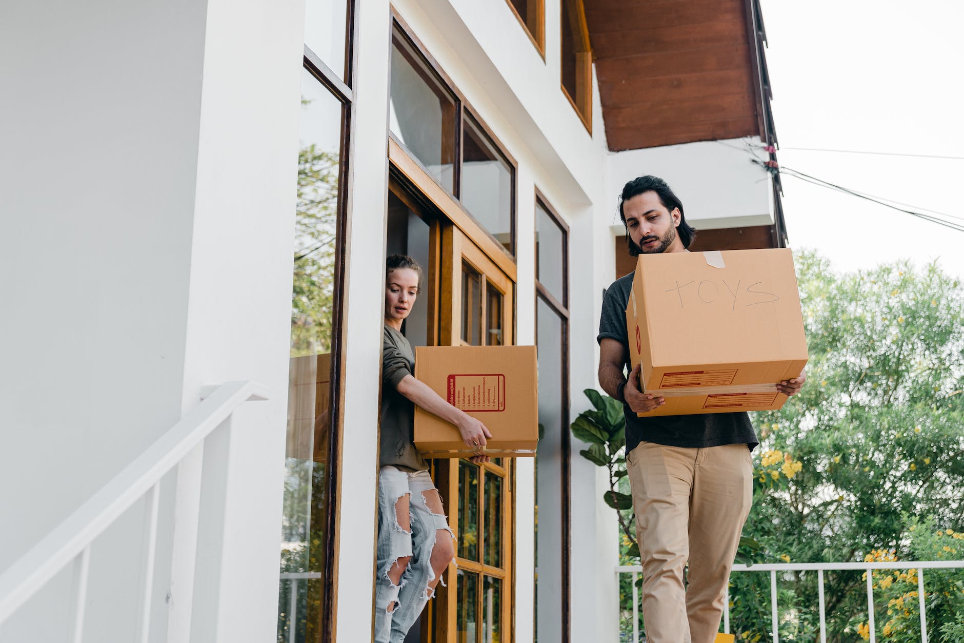 couple carrying carton boxes while moving out of old home