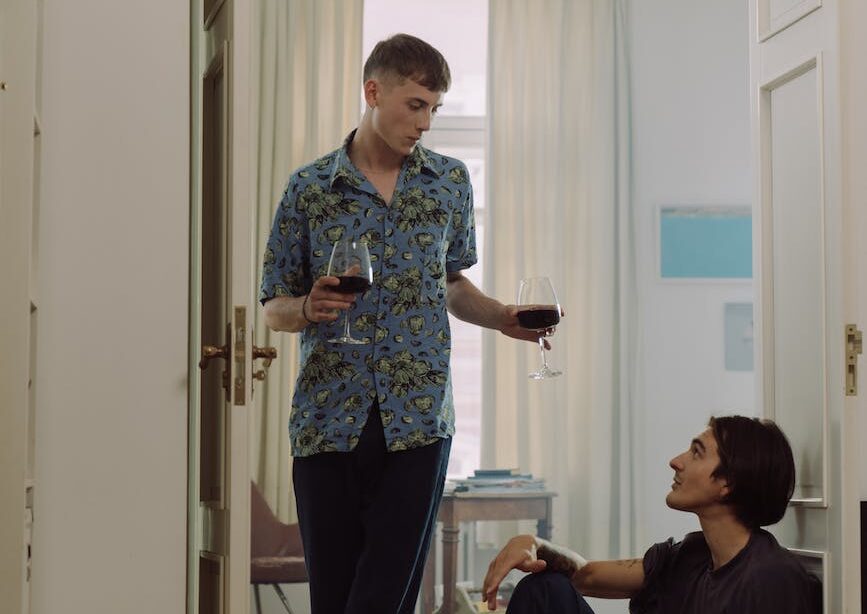 a man in blue polo holding wine glasses