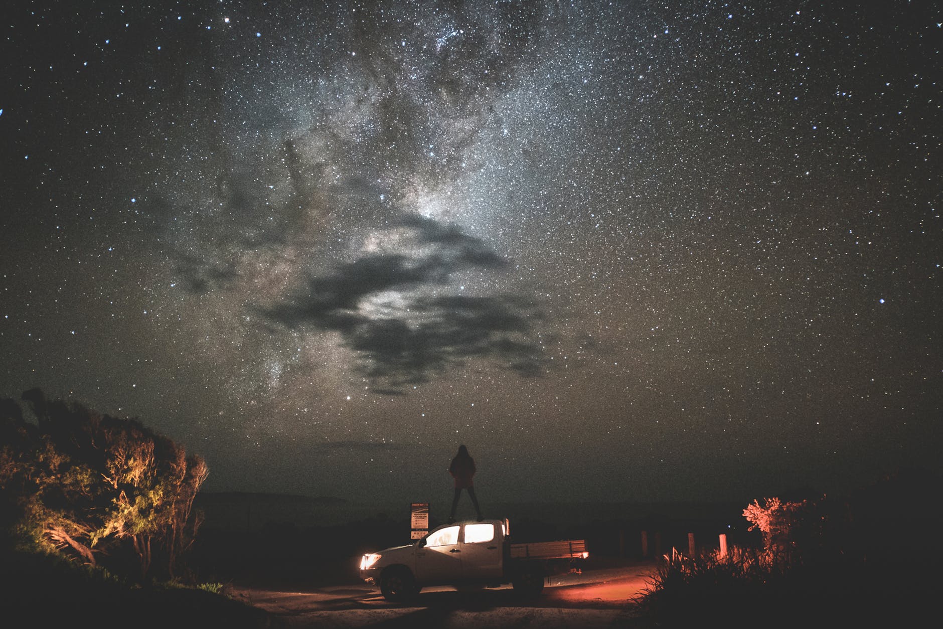 traveler standing on car at starry night