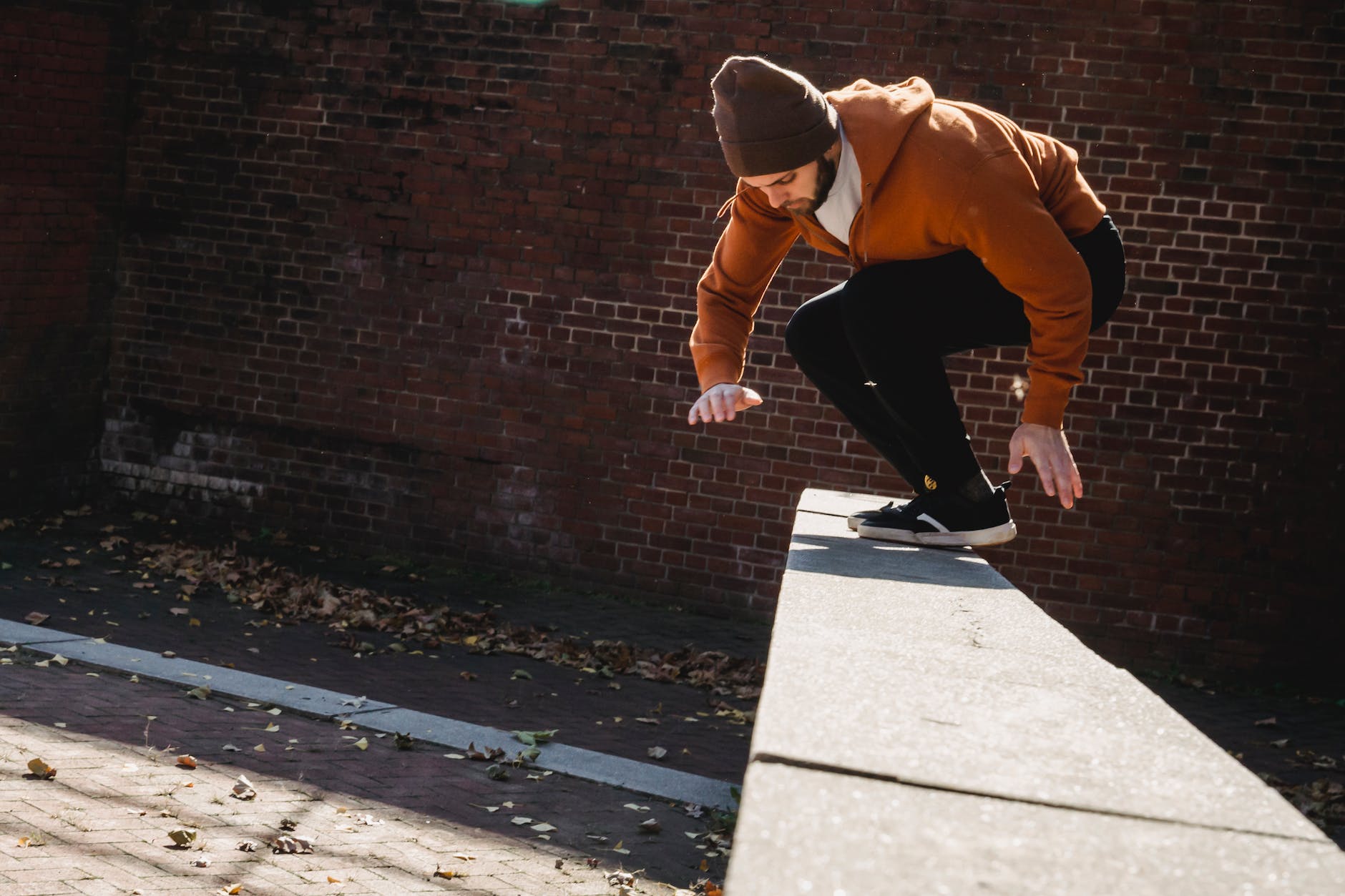 energetic man jumping on stone railing