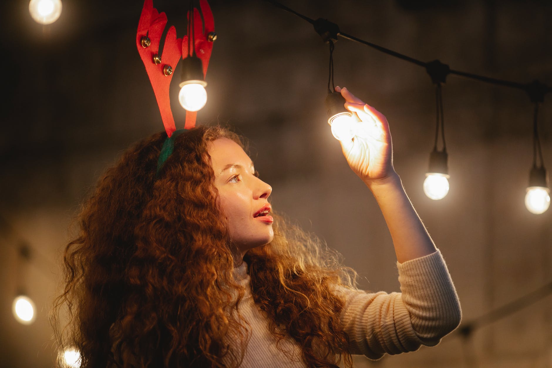 surprised woman standing under glowing garland with bulbs