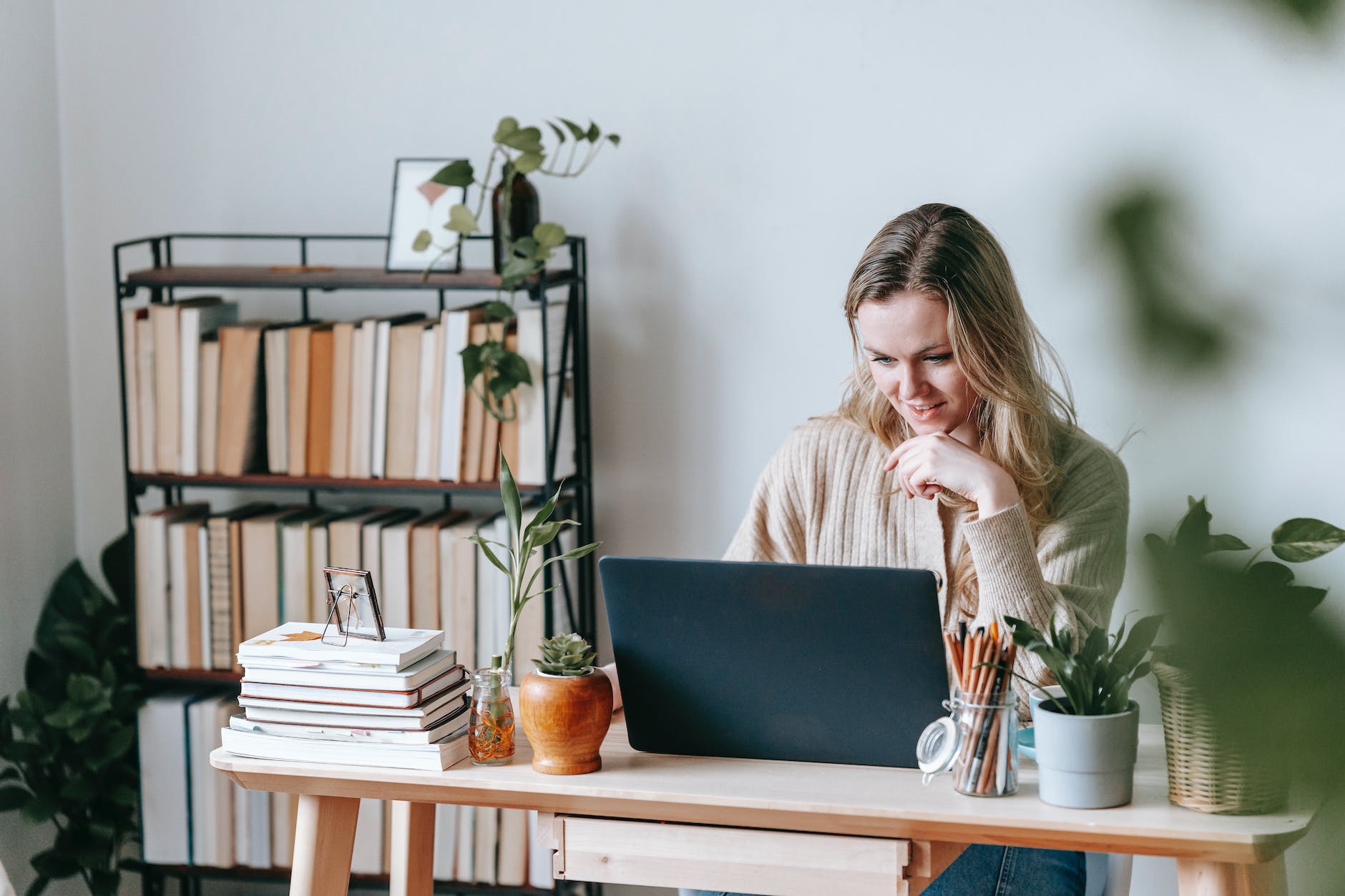 smiling freelancer working on laptop against bookcase at home desk