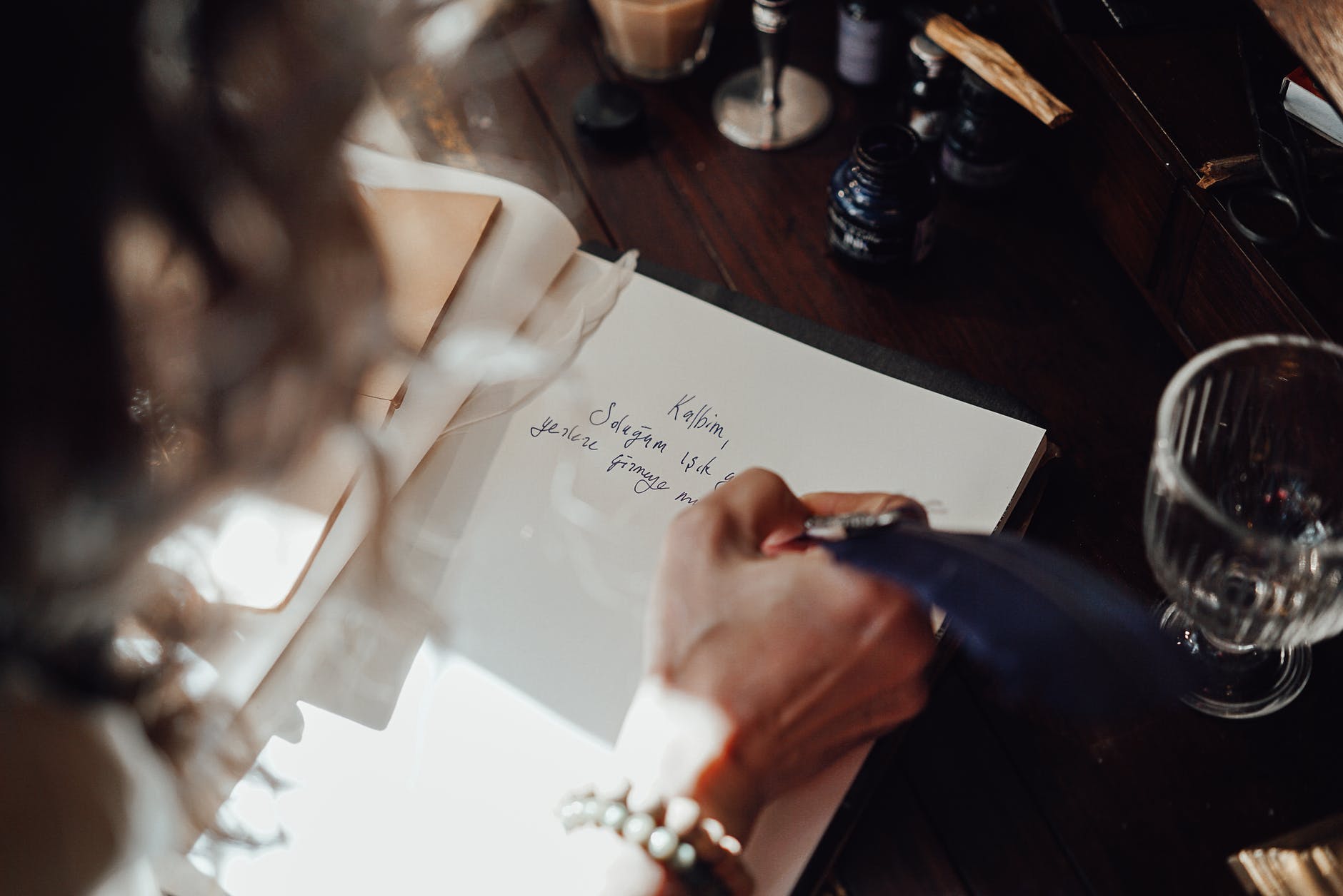 crop author writing novel in copybook with feather at table