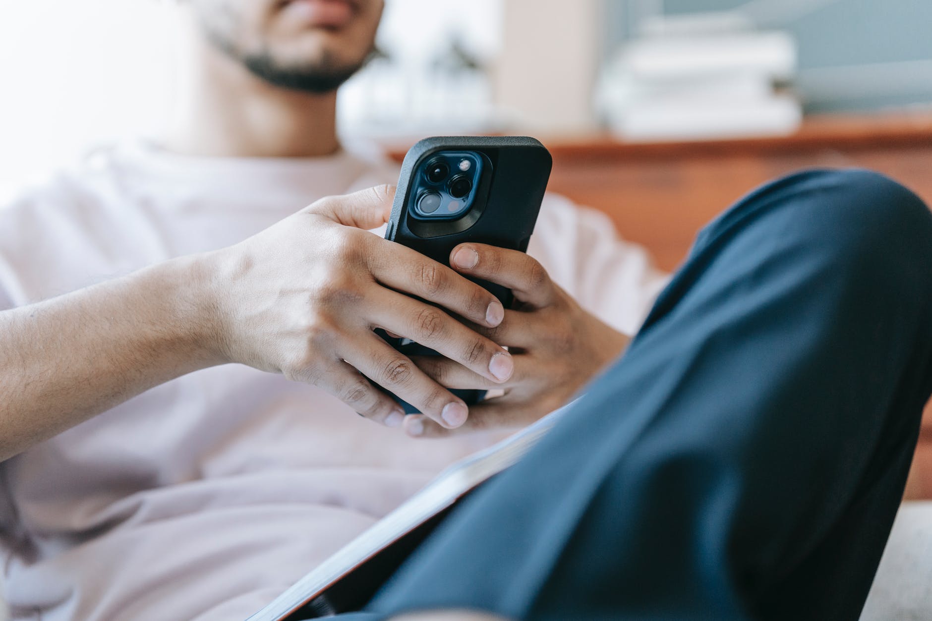 crop bearded man using smartphone in living room